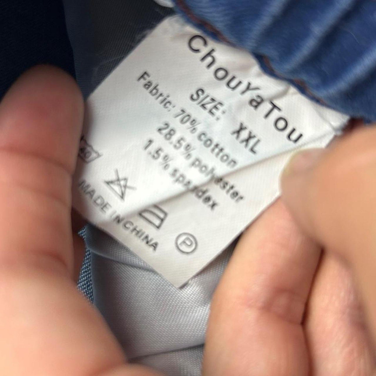 Clothing label with 'ChouYaTou' branding and size information held by a person.
